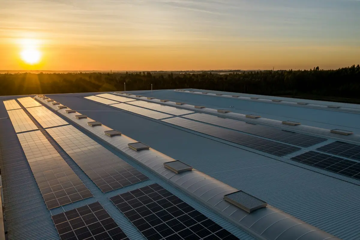 Paneles solares instalados sobre un techo industrial al atardecer